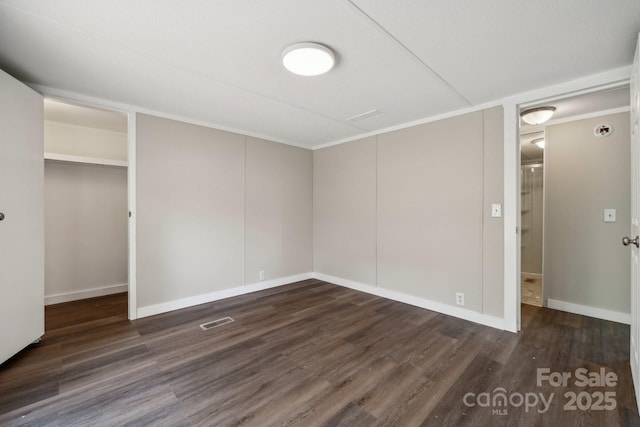 unfurnished bedroom with dark wood finished floors, a closet, baseboards, and ornamental molding