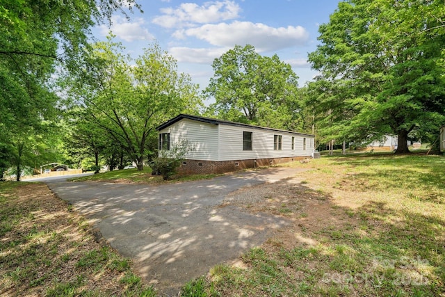view of home's exterior with crawl space and driveway