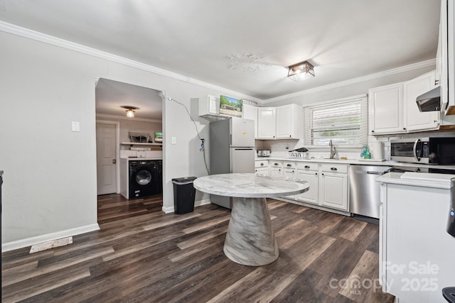 1917 Tom Sadler Rd, Charlotte, NC 28214 - kitchen featuring stainless steel appliances, washer / dryer, white cabinets, dark wood-style floors, and ornamental molding