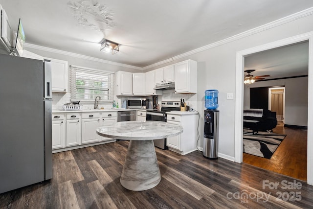1917 Tom Sadler Rd, Charlotte, NC 28214 - kitchen featuring stainless steel appliances, under cabinet range hood, backsplash, dark wood finished floors, and ornamental molding