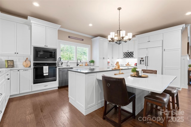 kitchen featuring built in appliances, ornamental molding, decorative backsplash, a chandelier, and a kitchen island
