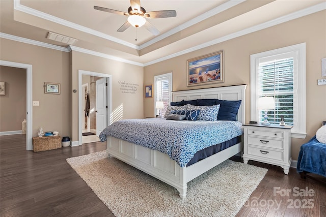 bedroom with a tray ceiling, multiple windows, dark wood-style flooring, and ornamental molding