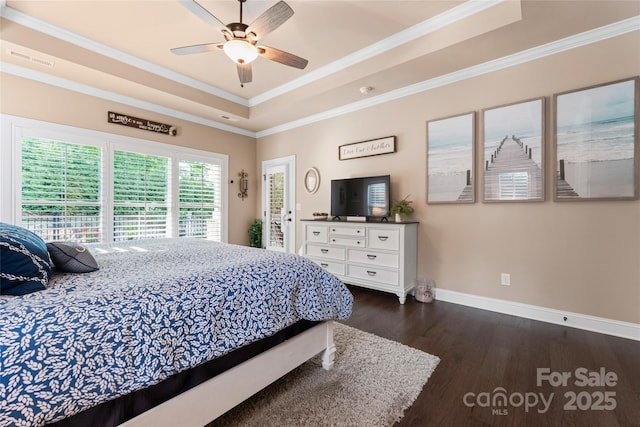 bedroom with a raised ceiling, baseboards, dark wood-type flooring, ornamental molding, and ceiling fan