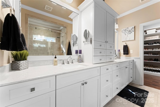 full bath with crown molding, double vanity, tiled shower, tile patterned floors, and a walk in closet