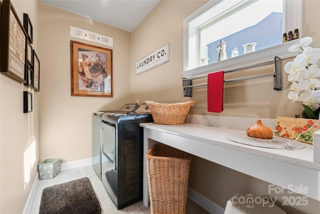 laundry room with washing machine and dryer, baseboards, and light tile patterned floors