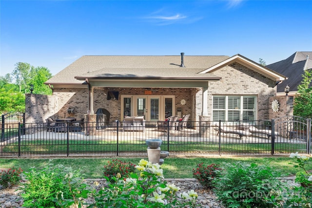 rear view of property with a patio, fence, brick siding, and french doors