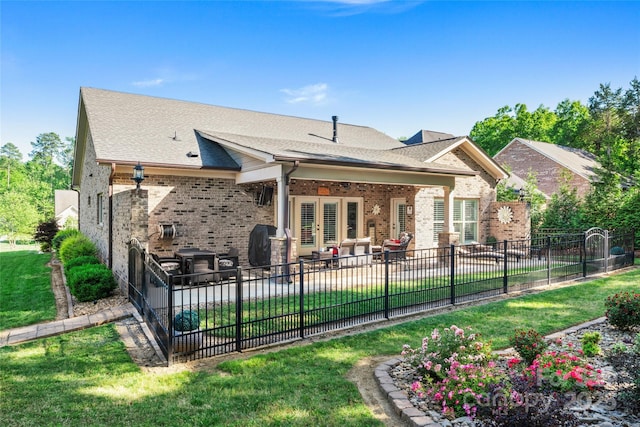 back of property with a patio, brick siding, french doors, and roof with shingles