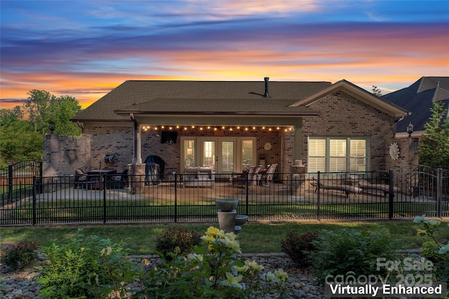 back of property at dusk with a patio area, brick siding, and french doors