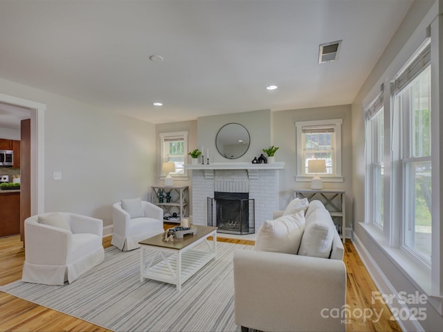 living room featuring light wood-type flooring, a fireplace, recessed lighting, and baseboards