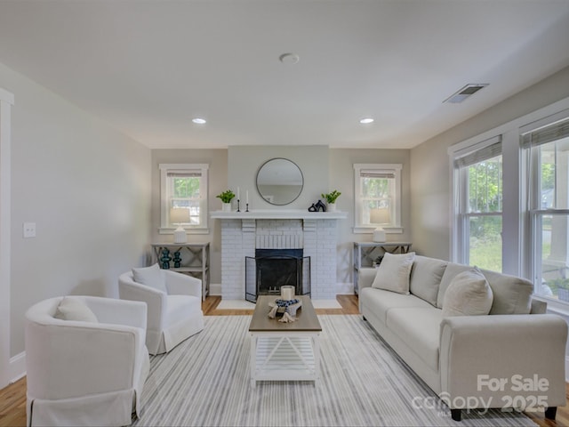 living area featuring wood finished floors, plenty of natural light, a fireplace, recessed lighting, and baseboards