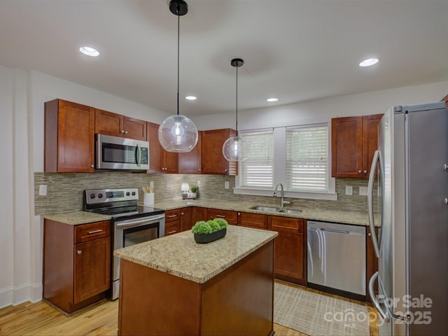 kitchen featuring appliances with stainless steel finishes, a sink, light wood-type flooring, tasteful backsplash, and light stone counters