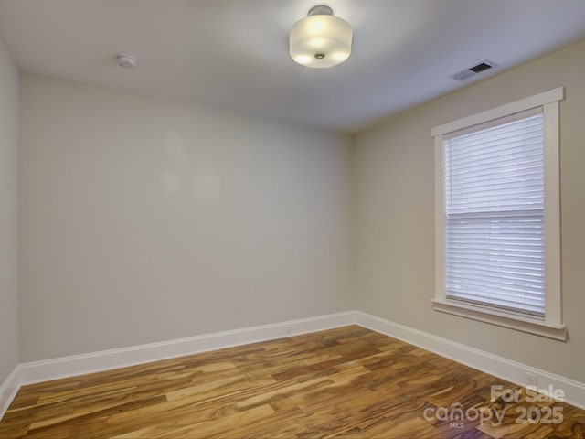 spare room with baseboards, wood finished floors, and a smoke detector