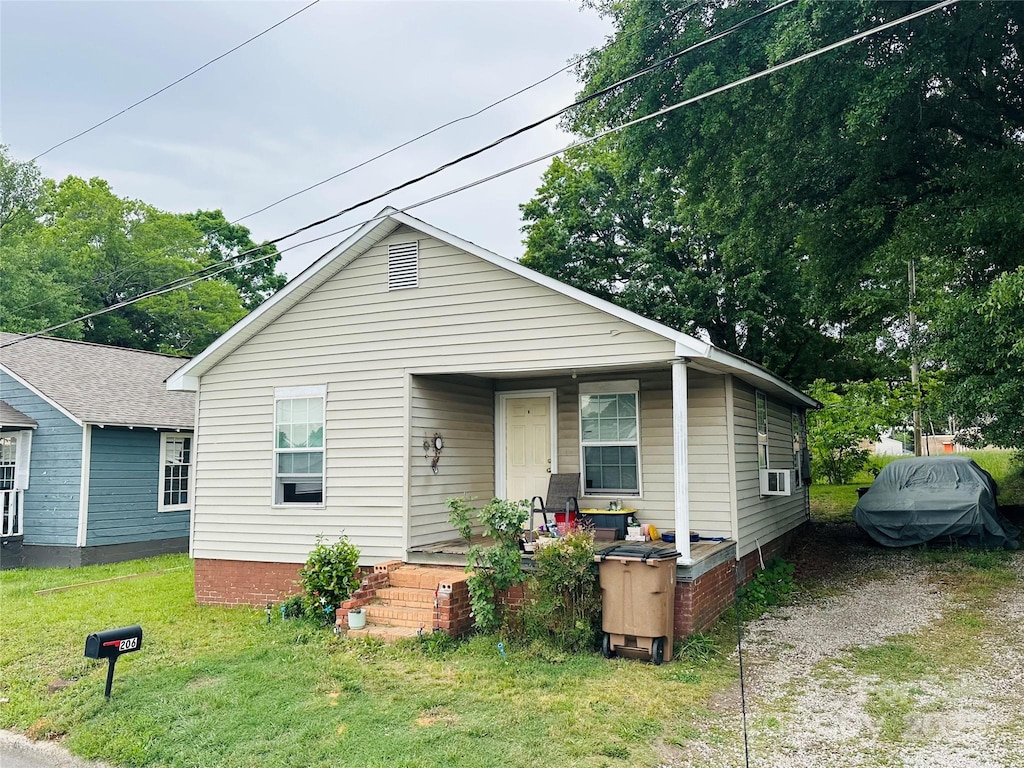 view of front of house featuring covered porch, a front yard, and cooling unit
