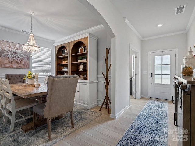5581 Soft Shell Dr, Lancaster, SC 29720 - dining area with arched walkways, light wood-style flooring, crown molding, a chandelier, and baseboards