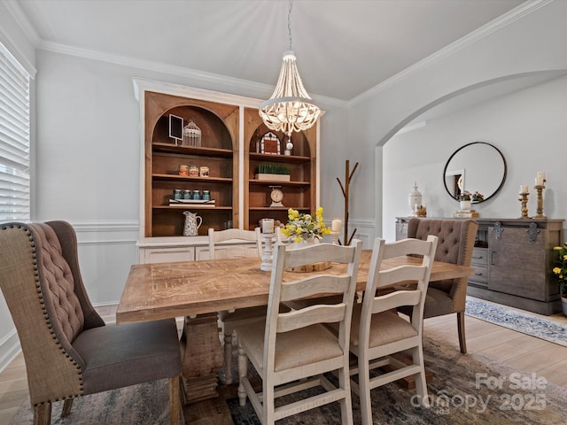 5581 Soft Shell Dr, Lancaster, SC 29720 - dining space with ornamental molding, light wood-type flooring, a chandelier, wainscoting, and arched walkways