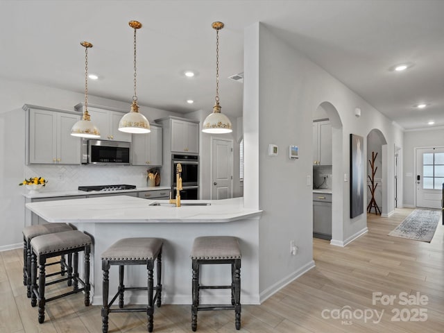 5581 Soft Shell Dr, Lancaster, SC 29720 - kitchen with stainless steel appliances, arched walkways, gray cabinets, a kitchen bar, and backsplash
