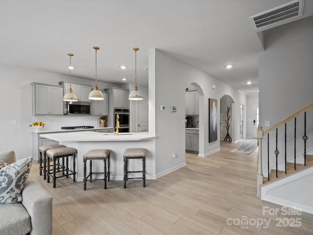 5581 Soft Shell Dr, Lancaster, SC 29720 - kitchen with stainless steel appliances, arched walkways, gray cabinetry, a breakfast bar area, and light countertops