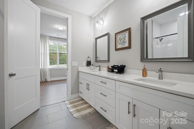 685 Knollcrest Dr NE, Concord, NC 28025 - bathroom with double vanity, baseboards, tiled shower, and tile patterned flooring