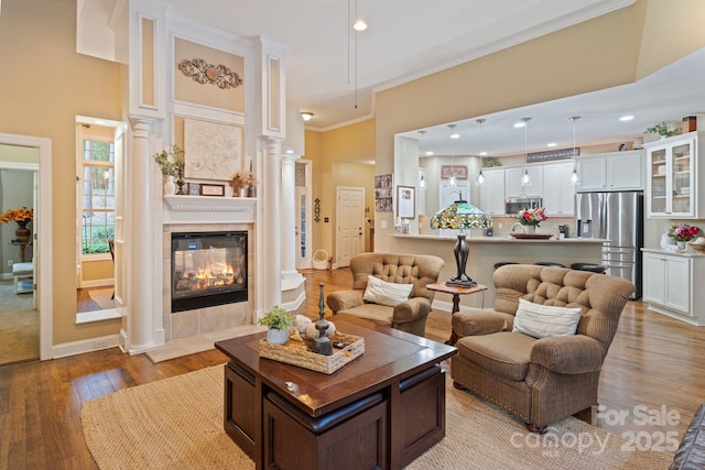 131 Sierra Woods Dr, Troutman, NC 28166 - living area with ornate columns, hardwood / wood-style floors, a tile fireplace, ornamental molding, and baseboards