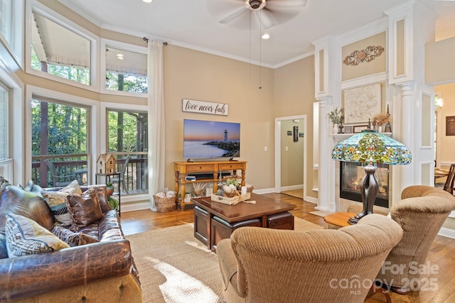 131 Sierra Woods Dr, Troutman, NC 28166 - living room featuring a high ceiling, decorative columns, a ceiling fan, wood finished floors, and crown molding