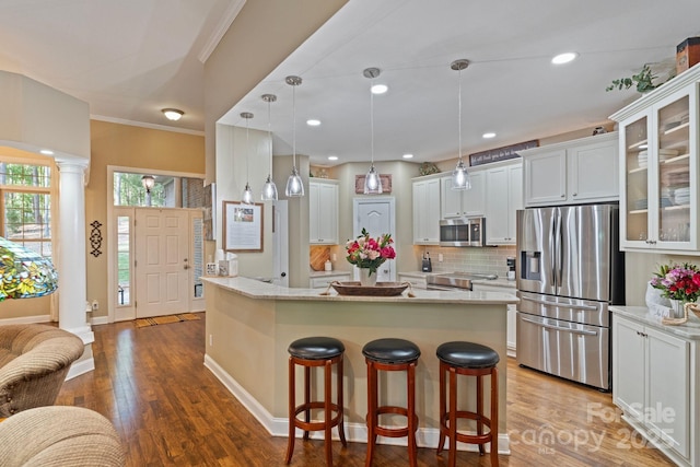 131 Sierra Woods Dr, Troutman, NC 28166 - kitchen with appliances with stainless steel finishes, a kitchen bar, wood finished floors, glass insert cabinets, and decorative backsplash
