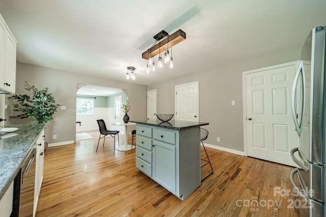 3387 Passmore Rd, Rock Hill, SC 29730 - kitchen with stainless steel appliances, a breakfast bar area, white cabinetry, light wood-type flooring, and baseboards