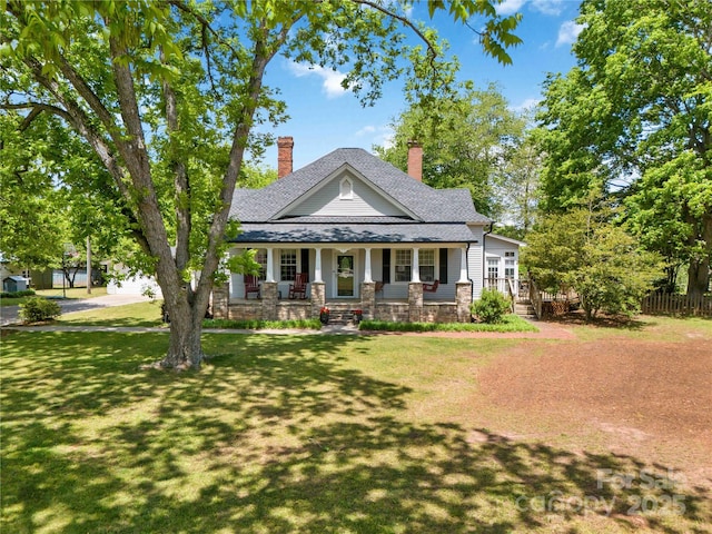 view of front of property with a porch, a chimney, and a shingled roof