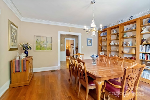 dining area with a chandelier, ornamental molding, wood finished floors, and baseboards