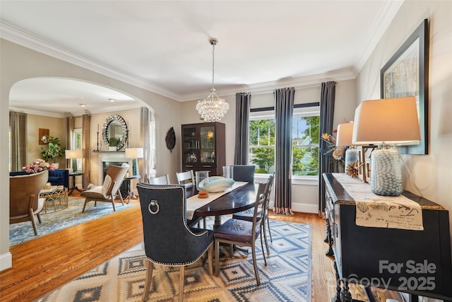1701 Dearmon Dr, Charlotte, NC 28205 - dining area featuring arched walkways, a chandelier, light wood-style flooring, ornamental molding, and baseboards