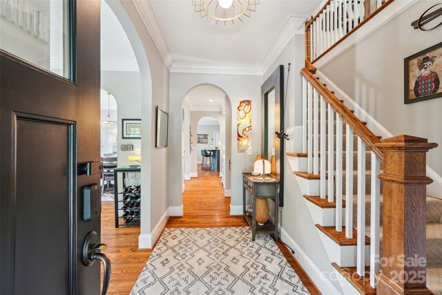 1701 Dearmon Dr, Charlotte, NC 28205 - entrance foyer with arched walkways, wood finished floors, ornamental molding, stairs, and baseboards