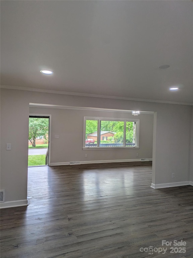 empty room with ornamental molding, plenty of natural light, baseboards, recessed lighting, and dark wood-style flooring