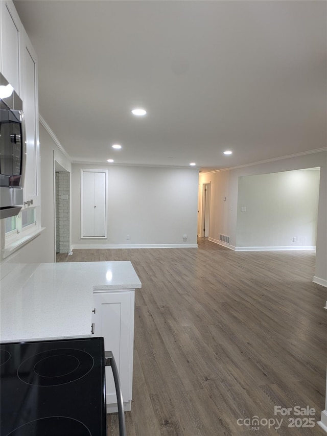 unfurnished living room featuring wood finished floors, baseboards, recessed lighting, and crown molding
