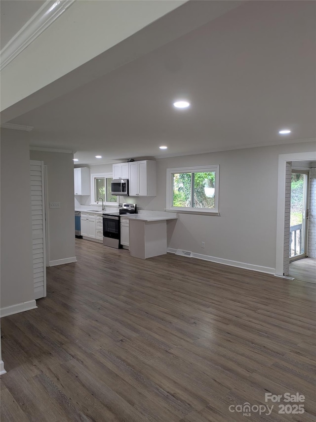 unfurnished living room with a sink, recessed lighting, crown molding, baseboards, and dark wood-style floors