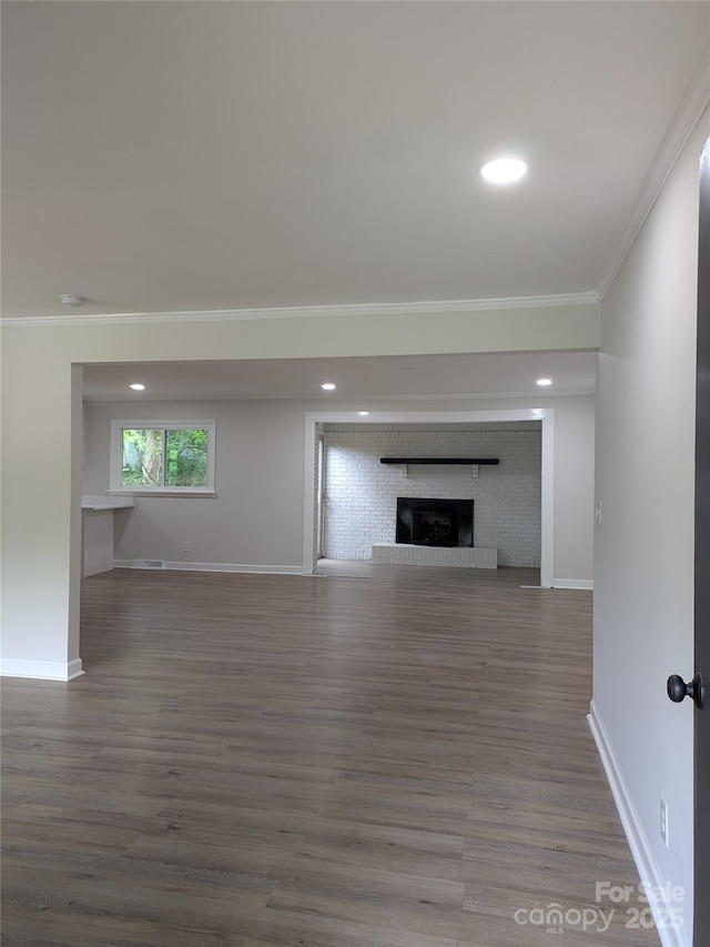 unfurnished living room with crown molding, baseboards, a fireplace, wood finished floors, and recessed lighting