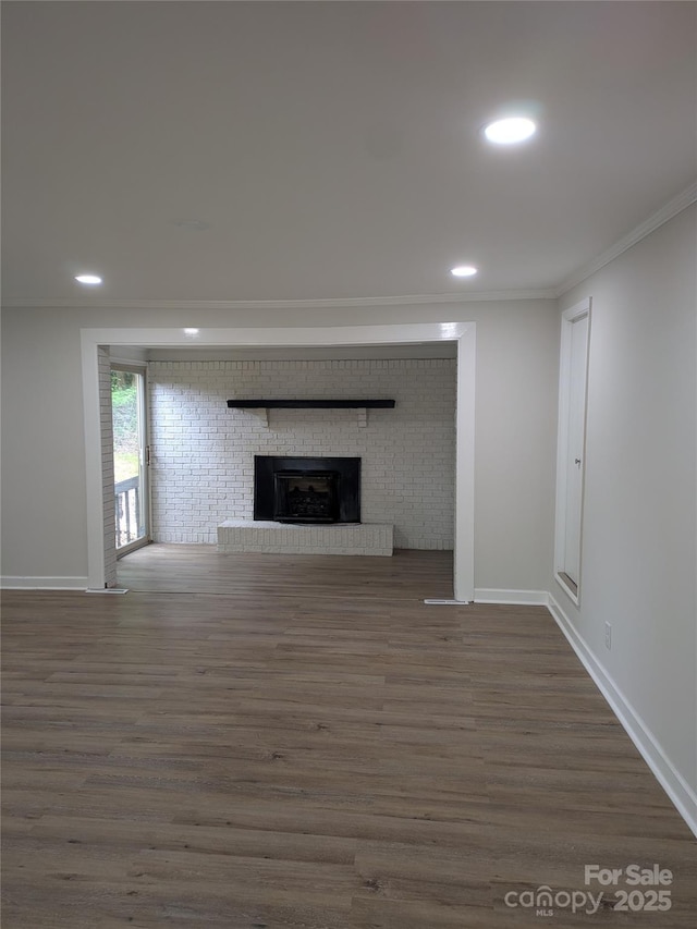 unfurnished living room with crown molding, wood finished floors, a fireplace, baseboards, and recessed lighting