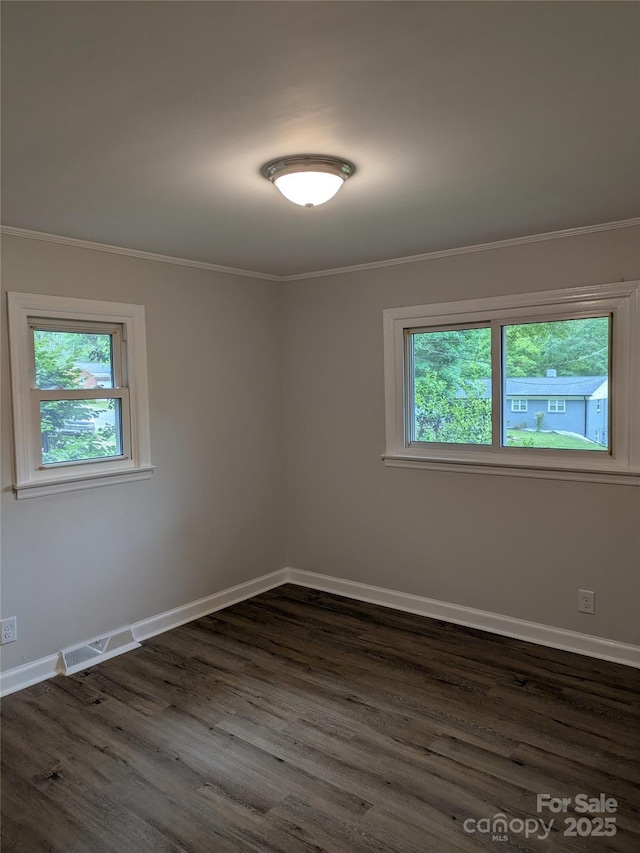 unfurnished room with plenty of natural light, dark wood-style floors, ornamental molding, and baseboards