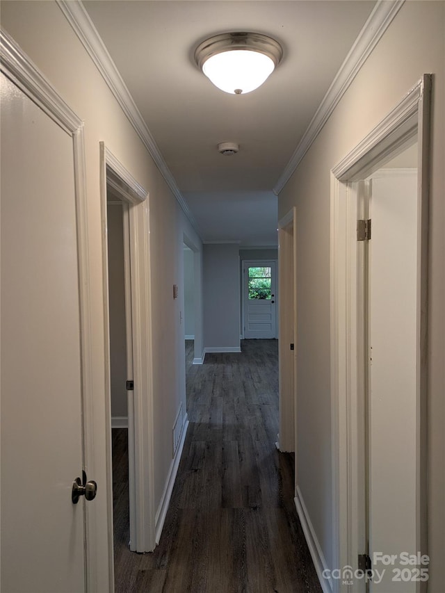 hall with dark wood-style flooring, crown molding, and baseboards