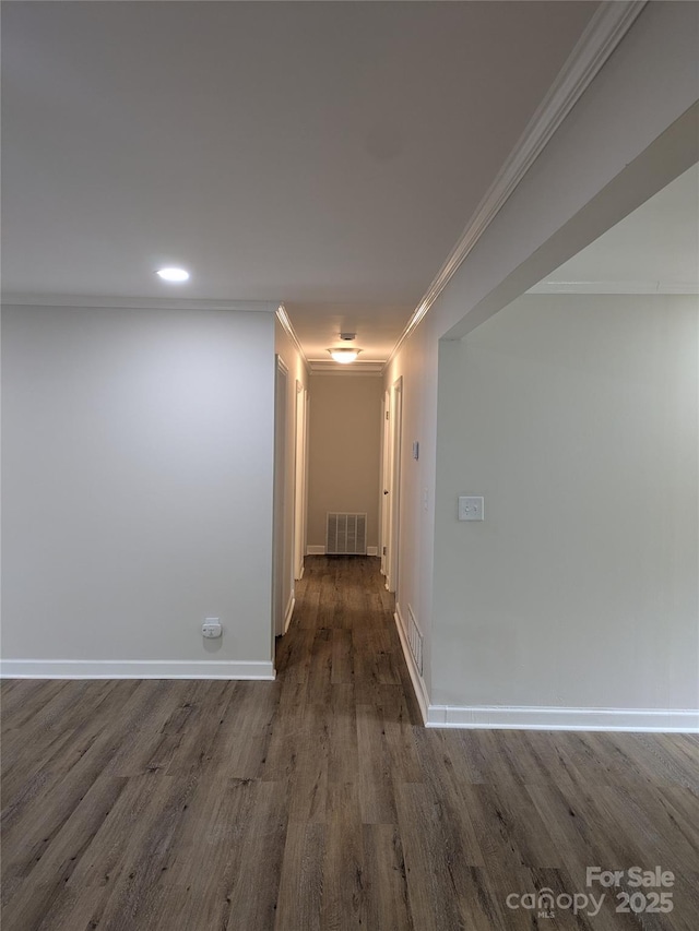 hallway with wood finished floors, crown molding, baseboards, and recessed lighting