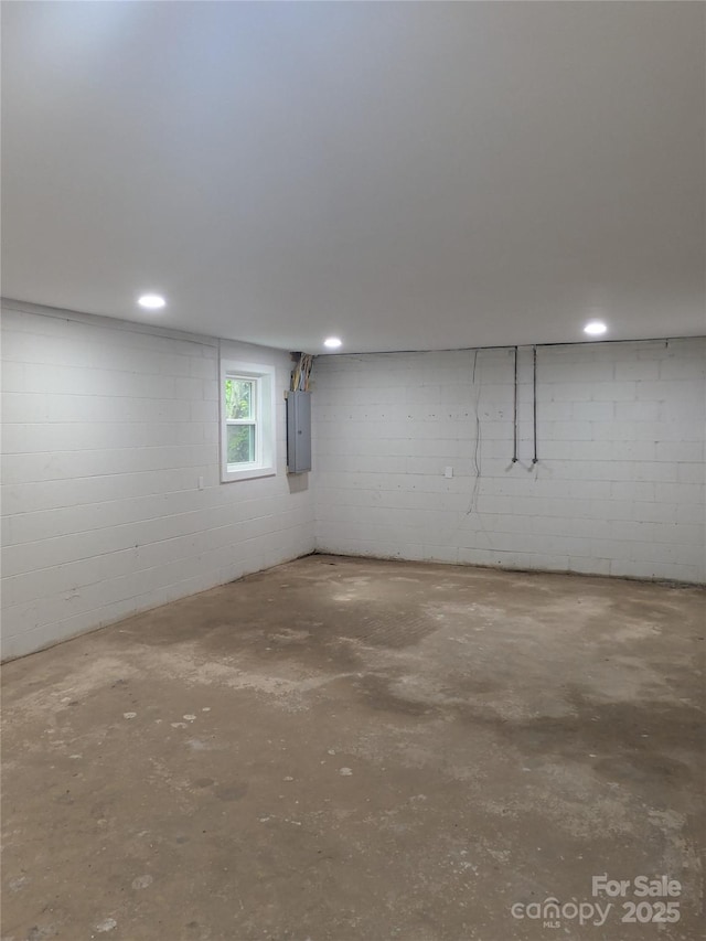 basement featuring electric panel and concrete block wall