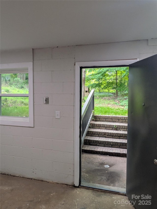 stairs with unfinished concrete flooring and concrete block wall