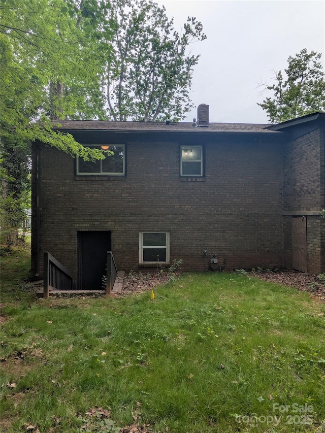 back of property featuring brick siding and a lawn