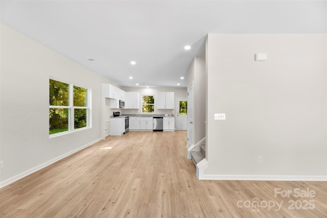 unfurnished living room featuring baseboards, light wood-type flooring, and recessed lighting