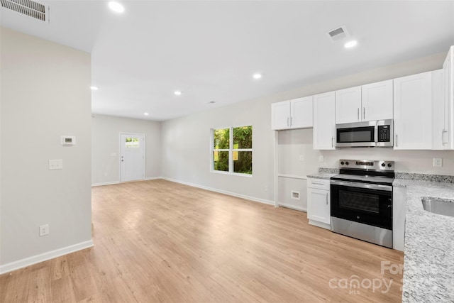 kitchen featuring appliances with stainless steel finishes, white cabinetry, recessed lighting, light wood finished floors, and baseboards