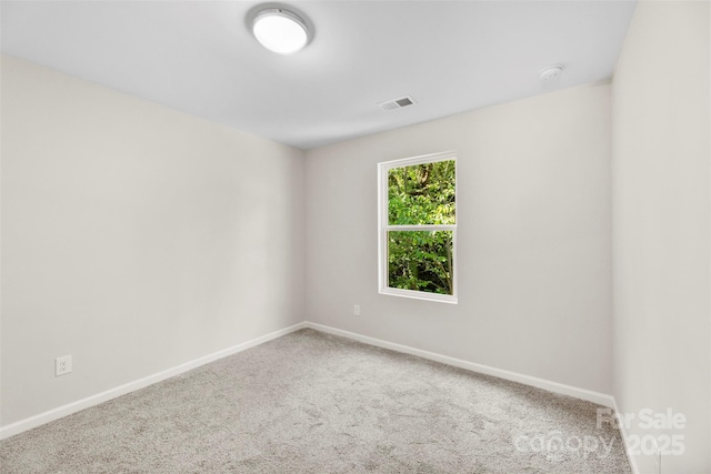 carpeted spare room with baseboards and a smoke detector