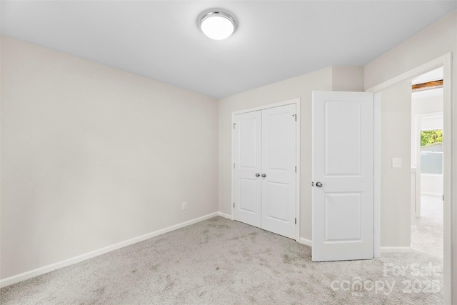 unfurnished bedroom featuring carpet floors, baseboards, and a closet