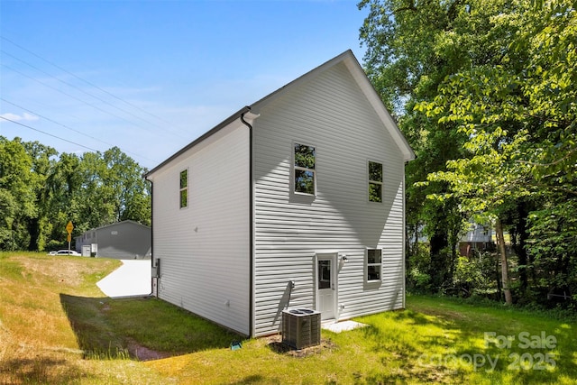 back of house with central air condition unit and a lawn