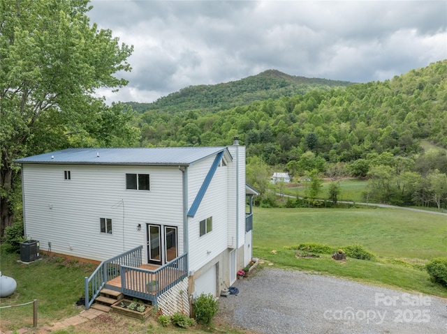 234 Snyder Farm Rd, Waynesville, NC 28786 - back of property featuring a forest view, central AC, a yard, an attached garage, and a wooden deck