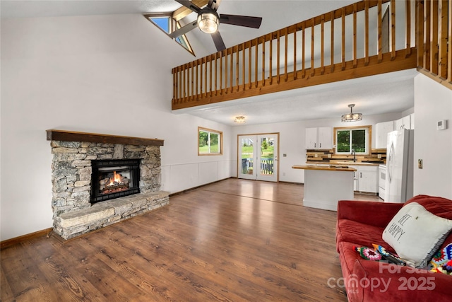 234 Snyder Farm Rd, Waynesville, NC 28786 - living room featuring wood finished floors, a ceiling fan, a stone fireplace, high vaulted ceiling, and baseboards