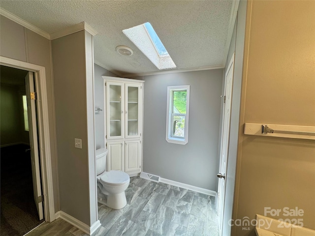 40 Mountainview Rd, Asheville, NC 28806 - bathroom featuring a skylight, crown molding, toilet, a textured ceiling, and wood finished floors