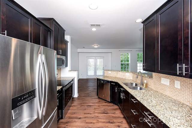 kitchen featuring appliances with stainless steel finishes, a sink, dark wood-style flooring, tasteful backsplash, and recessed lighting